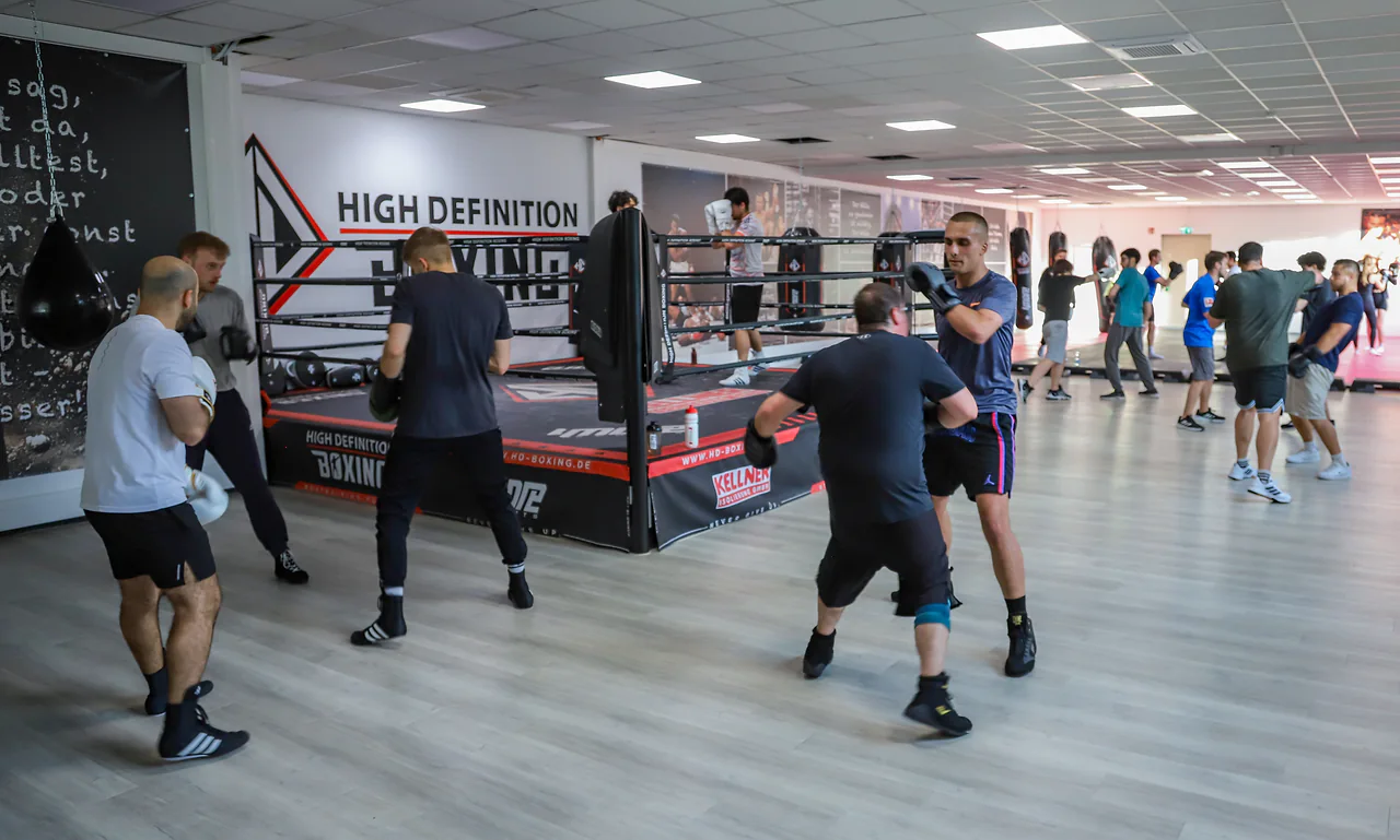 Volle Halle mit mehreren Trainingspaaren und Boxring