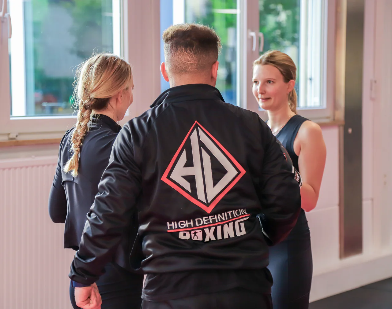 Trainer begleitet zwei Frauen bei einer Partnerübung